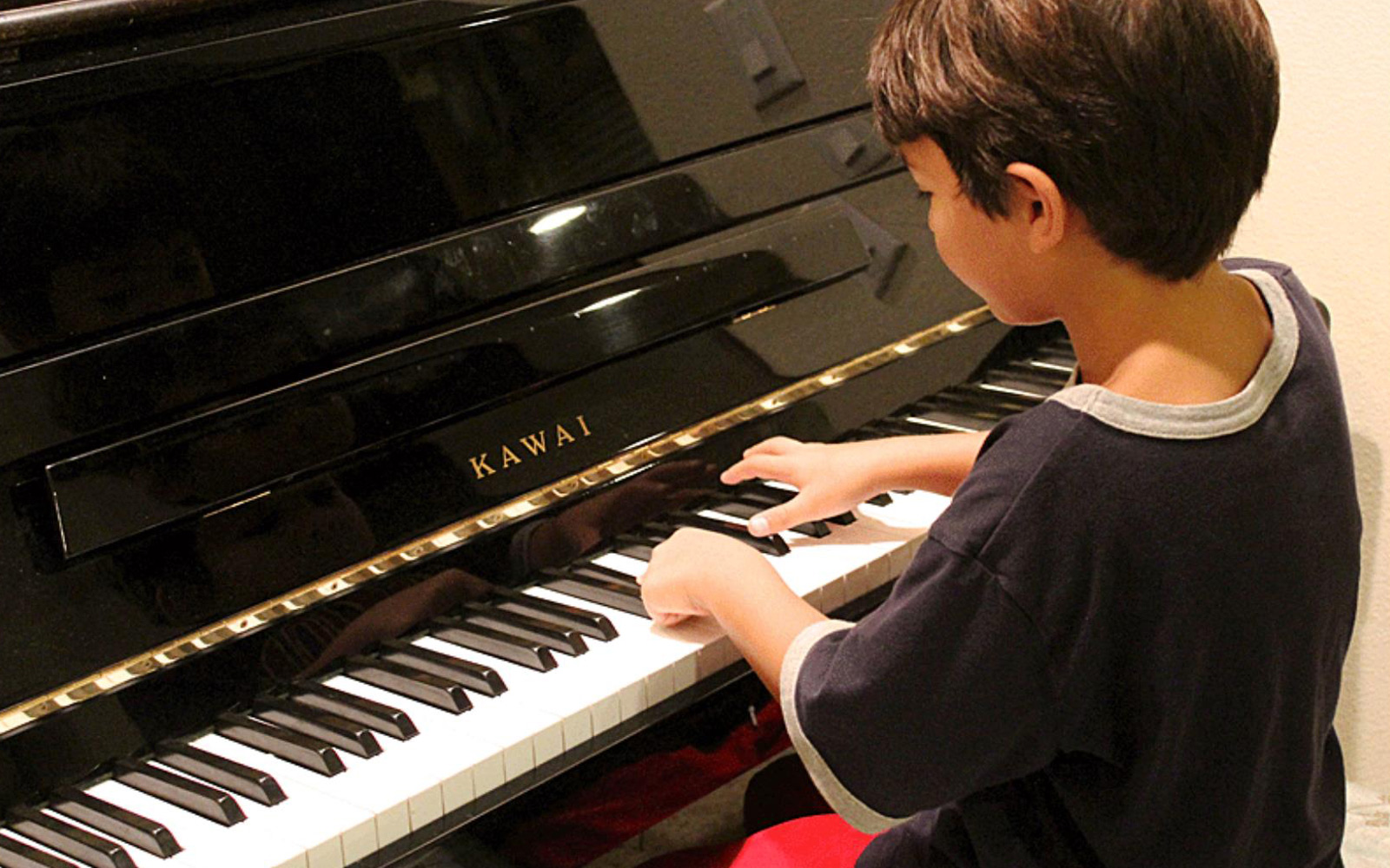 Kind sitzt am Klavier und spielt